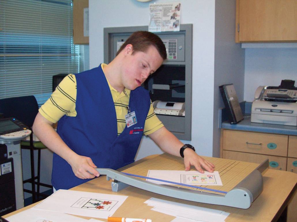 Edward Nesbitt, Next Steps class of 2011 Edward Nesbitt when he was at Next Steps, working at one of his internships. He is wearing a blue worker vest and using a cutter to trim some paper.