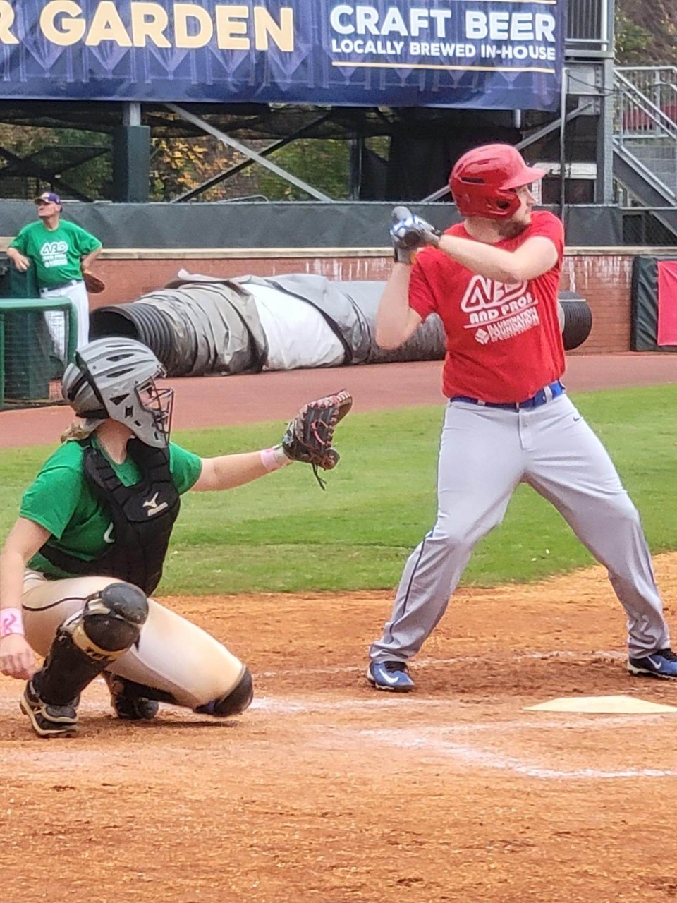 baseball player swing a bat with a catcher behind him at home plate
