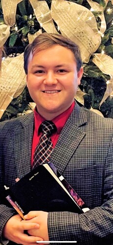 headshot of Haiden, a young man in a suit with short blonde hair and a smile