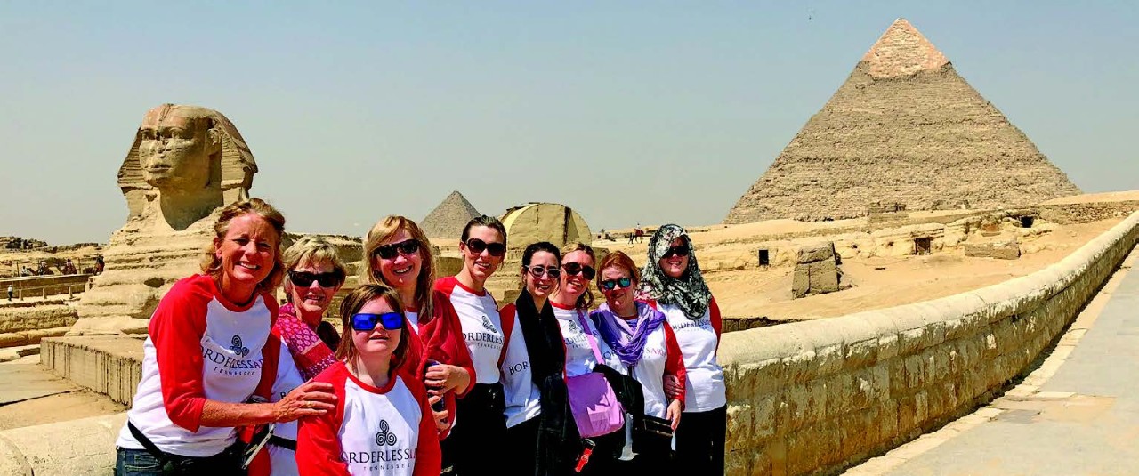 BG 93 - Borderless Arts Egypt nine women of various ages leaning against a short wall. In the background you can see Egyptian monuments