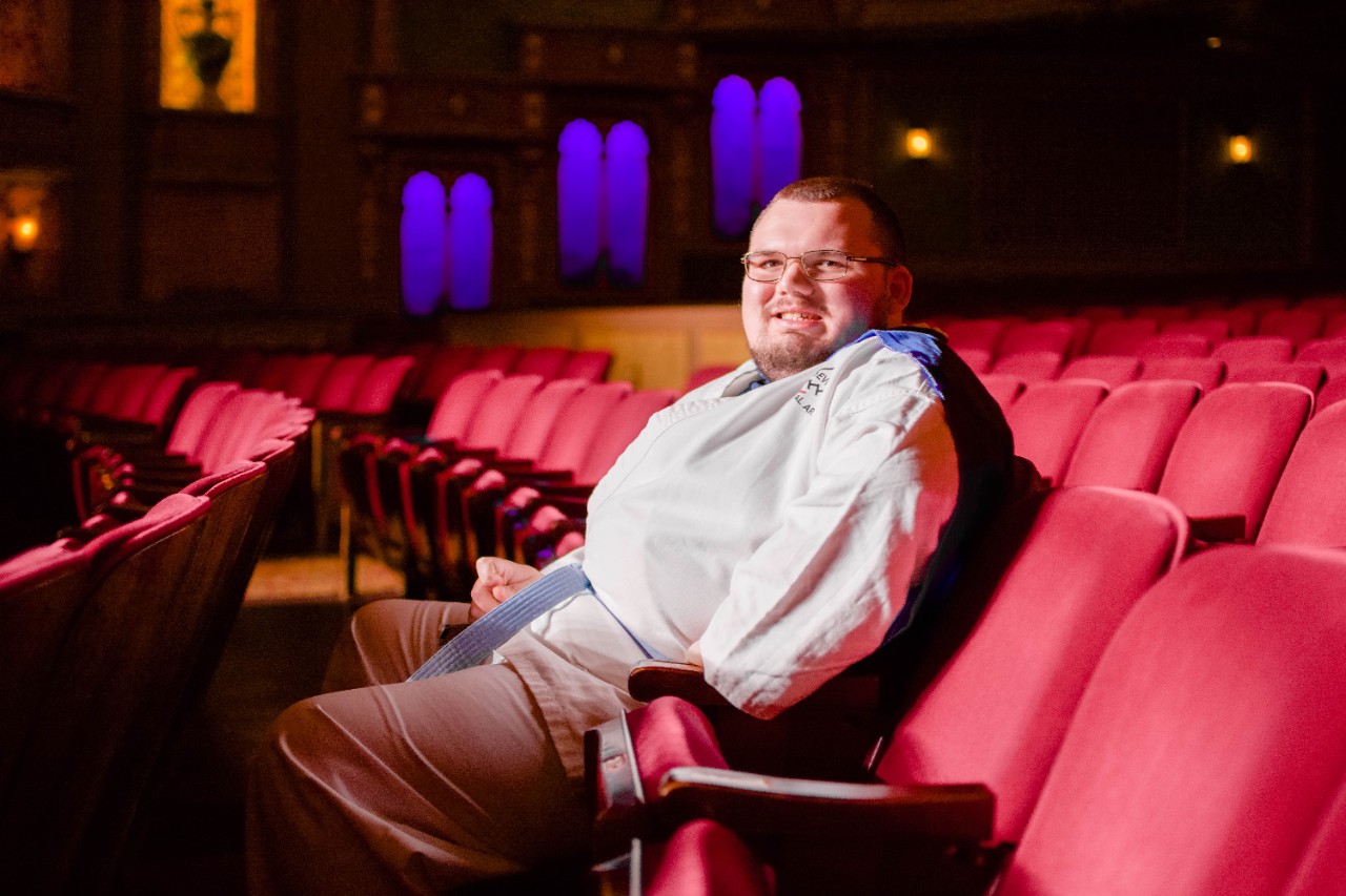 Man sitting in rows of seats at Tennessee theatre, colorful lights in the background