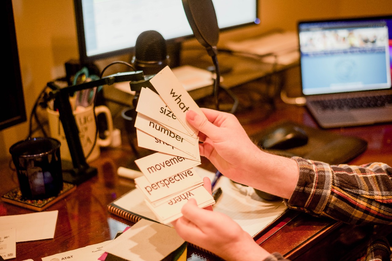 Ben holds up various cards with words listed on them that he uses in tutoring classes