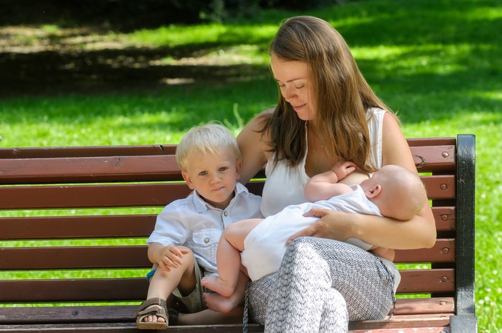 Women breastfeeding infant in park Women breastfeeding infant in park