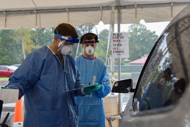 Sgt. Robert Neal (left), an Infantryman assigned to 2nd Squadron, 278th Armored Cavalry Regiment, and Spc. Jason Bahr, a Combat Medic with the 208th Area Support Medical Company, perform COVID-19 testing at a Regional Assessment Site in Montgomery County, Sept. 28. Since late March, up to 2,000 Tennessee National Guardsmen have been activated in some capacity to provide support to the Tennessee Department of Health in their fight against COVID-19. (photo by Staff Sgt. Timothy Cordeiro) Soldiers in protective gear speak with a civilian in a vehicle in order to test them for Covid-19