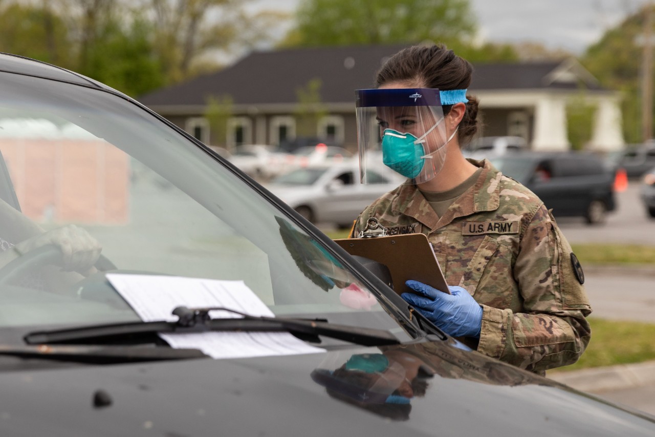 Sgt. Leann Roggensack, a field artilleryman with the 278th Armored Cavalry Regiment, works as a registered nurse in her civilian occupation. She is one of many Tennessee Guardsmen who have volunteered to help test Tennessee residents for COVID-19. (Photo by Sgt. Sarah Kirby). Female Tennessee National Guard Soldier in protective gear giving COVID-19 tests at drive-thru facility