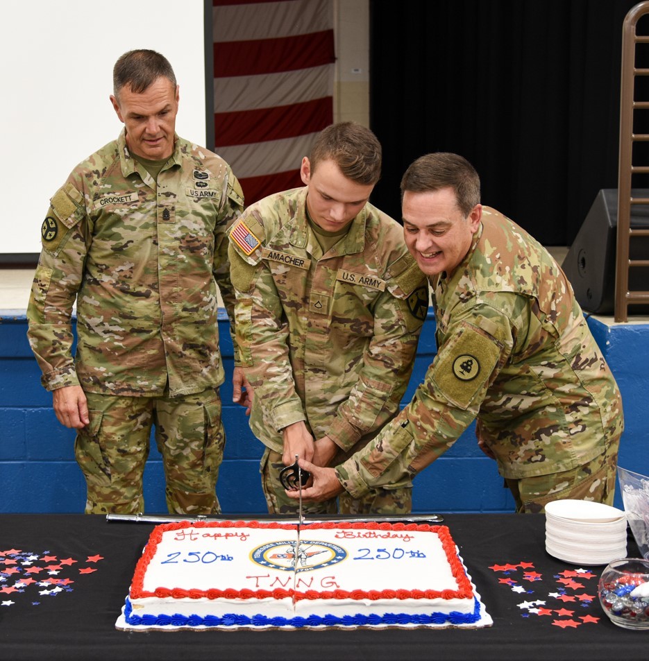 Tennessee’s Senior Enlisted Leader, Command Sgt. Maj. Dale Crockett, looks on as Pfc. Christian Amacher and Col. Mark Phillips perform the ceremonial cake cutting during the Tennessee National Guard’s 250th birthday celebration at Nashville’s Joint Force Headquarters on August 16. (photo by retired Sgt. 1st Class Edgar Castro)