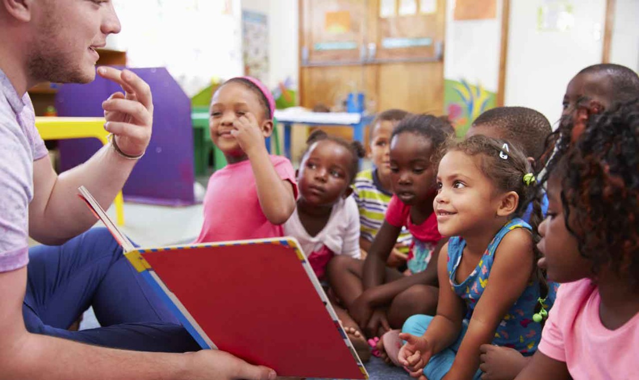 Early Childhood Page Male teacher reading book to young children